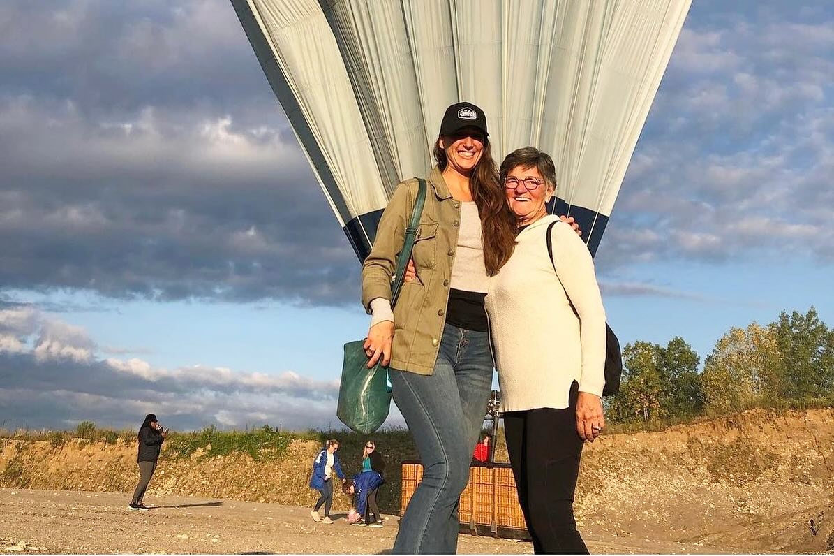 Sundance hot air balloon floating over green countryside at golden hour